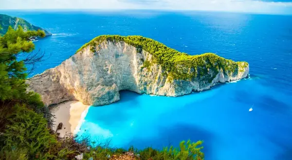 Widok na zatokę Navagio, słynną plażę w Grecji, z klifem porośniętym zielenią i turkusową wodą. Idealne miejsce na wakacje, jak z pocztówki z greckich miast.