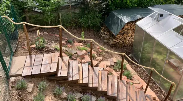 Eine **einfache Gartentreppe selber bauen** ist hier gelungen. Holzstufen mit Seilgeländer führen durch einen Hang mit Lavendel.
