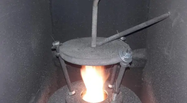 Płomień w piecu na ekogroszek. Widoczny metalowy deflektor z regulacją, który poprawia spalanie.