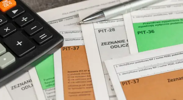 Kalkulator i długopis na dokumentach PIT-37 i PIT-36. Zastanawiasz się, kiedy pit 36, a kiedy 37?