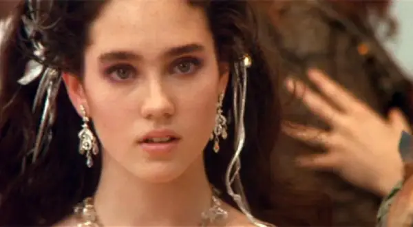 Jennifer Connelly w filmach, z burzą ciemnych włosów ozdobionych srebrnymi dodatkami i wyrazistym makijażem oczu.