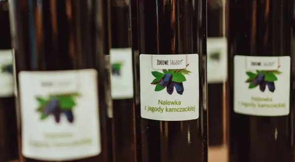 Butelki z nalewką z jagody kamczackiej. Etykieta przedstawia jagody i liście.