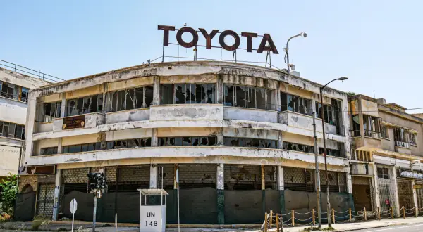 Opuszczony salon Toyoty, symbol miasta duchów na Cyprze, z wybitymi szybami i zniszczoną fasadą.