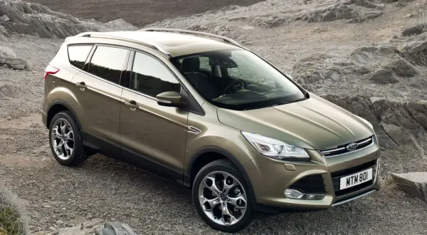 Złoty Ford Kuga na kamienistym podłożu. Poznaj jego wymiary i możliwości terenowe.