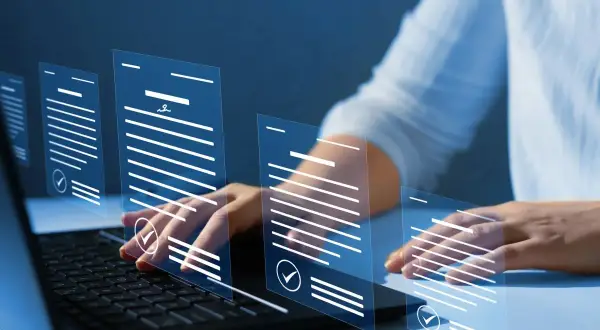 Ręce nad klawiaturą laptopa, wirtualne dokumenty unoszą się w powietrzu, symbolizując cyfrowe przetwarzanie wniosków, np. zaświadczenie o zameldowaniu.