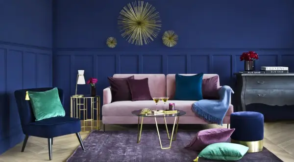 Elegancki salon z granatową ścianą, różową kanapą i złotymi dodatkami. Inspiracje dla odważnych.