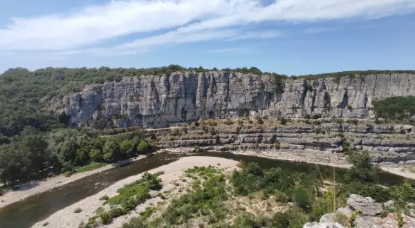 Un cirque de gens, des kayakistes profitent de la rivière au pied d'une falaise imposante.
