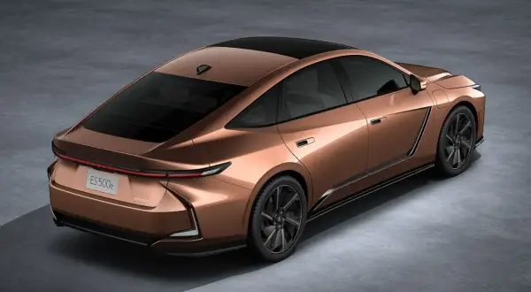 Nowy Lexus ES 500e w kolorze miedzianym, z czarnym dachem i przyciemnianymi szybami, prezentuje się elegancko na szarym tle.