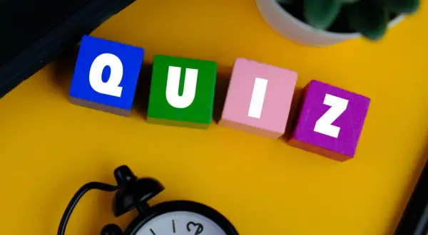 Kolorowe klocki z literami tworzą słowo QUIZ. Zegar i roślina sugerują, że czas sprawdzić swoją znajomość!