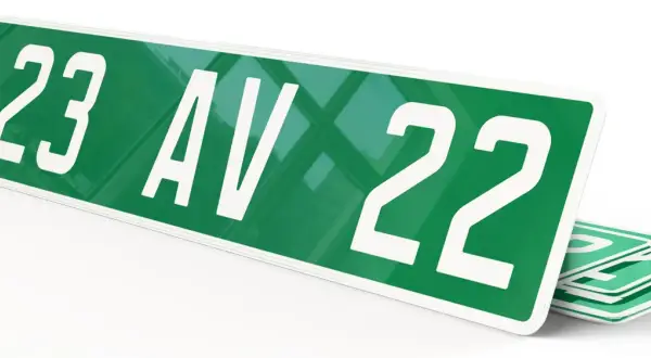 Plaque verte voiture avec "123 AV 22" en blanc. D'autres plaques similaires sont empilées en dessous.