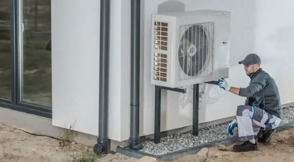 Un technicien vérifie une pompe à chaleur extérieure, étape clé pour le calcul rentabilité pompe à chaleur.