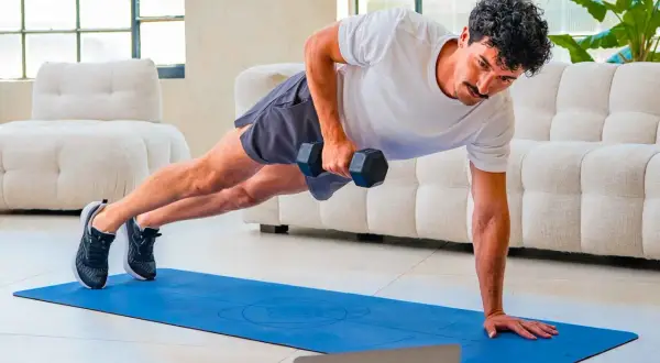 Uomo in posizione di plank con manubrio, esercizio per come migliorare la postura. Allenamento a casa.