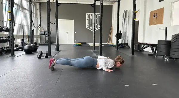 Frau macht Liegestütze im Fitnessstudio, ein Teil ihres plyometrischen Trainings.