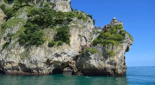 Escaleras y faros en Cantabria, con gente disfrutando del mar y la costa rocosa.