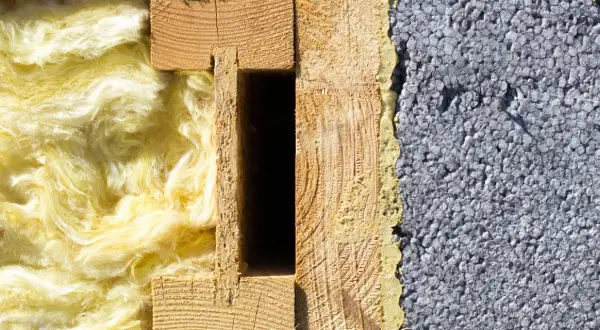 Przekrój ściany: z jednej strony puszysta wełna mineralna, z drugiej szary styropian, pośrodku drewniana konstrukcja.