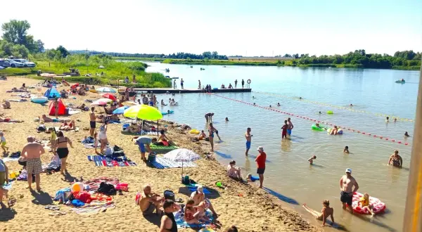 Ludzie odpoczywają na piaszczystej plaży nad rzeką, w krainie dolnej Wisły. Kąpiel, opalanie i relaks w upalny dzień.