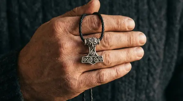 Dłoń trzyma wisiorek z młotem Thora, symbolem siły i ochrony. To jego znaczenie jest wciąż żywe.