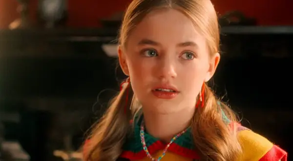 Holly Wheeler aus Stranger Things mit Zöpfen und einer bunten Halskette.