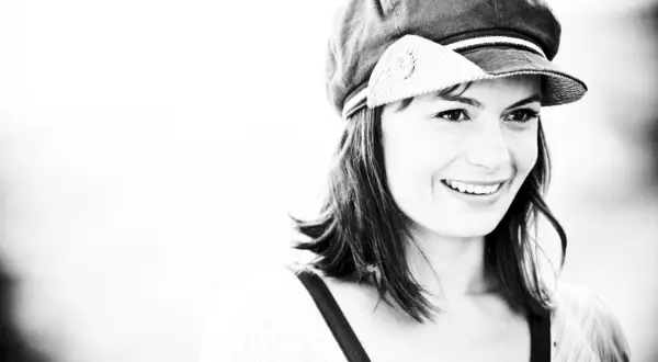Sorriso contagioso di Lisa Lelli con un cappello alla marinara, in un ritratto in bianco e nero.