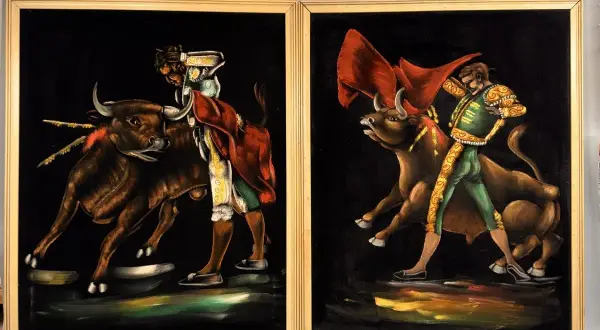 Two paintings by 1970s artists painters depict matadors facing bulls. The vibrant velvet art captures the drama of the bullfight.