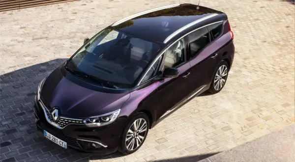 Elegancki, fioletowy Renault Initiale z chromowanymi relingami dachowymi stoi na brukowanym podjeździe.
