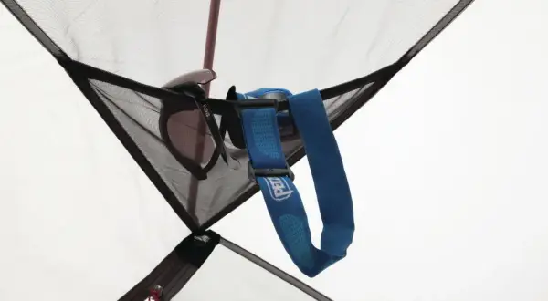 Okulary przeciwsłoneczne i latarka czołowa Petzl wiszą w siatkowej kieszonce namiotu MSR Elixir 2.