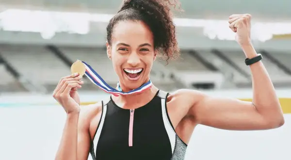 Atleta felice con medaglia d'oro dopo la corsa 10 km. Celebra la vittoria con un pugno alzato.