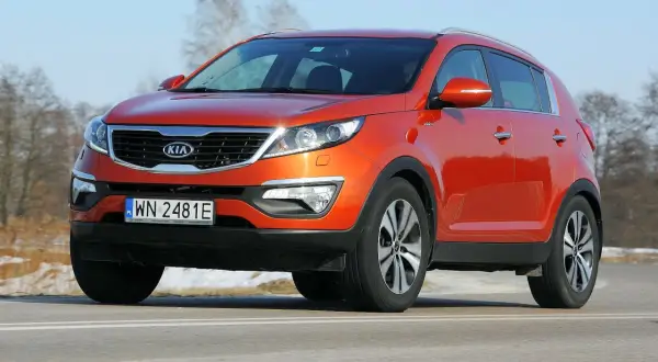 Pomarańczowy Kia Sportage 2012 na drodze, z widocznym numerem rejestracyjnym WN 2481E.