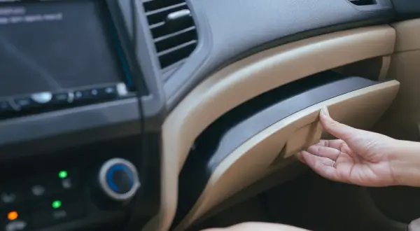 Mano apre il cassetto portaoggetti per recuperare i documenti obbligatori in auto.