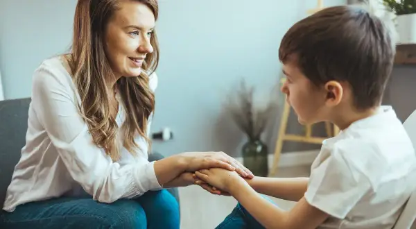 Kobieta wspiera chłopca, trzymając go za ręce. Orzeczenie o zagrożeniu niedostosowaniem społecznym może pomóc w uzyskaniu wsparcia.