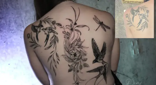 Ein detailliertes Backpiece Tattoo mit Schwalben, einer Libelle und einer großen Blume.