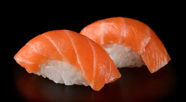 Dwa kawałki sushi z łososiem, idealna ryba do sushi, na czarnym tle.