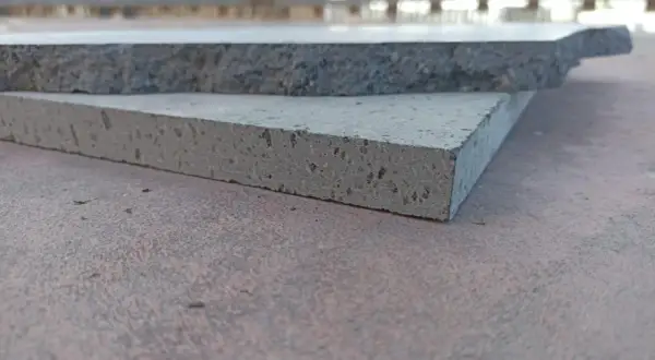 Due piastrelle in pietra lavica, una più chiara e porosa, l'altra più scura e compatta, mostrano la loro texture unica.