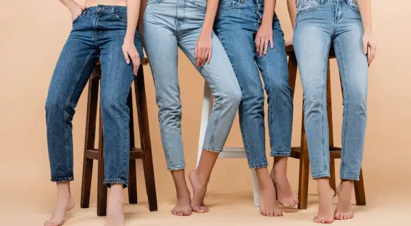 Cztery kobiety w różnych odcieniach jeansów siedzą na stołkach. Denim to materiał, który nigdy nie wychodzi z mody.