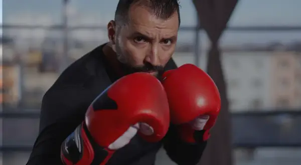 A focused boxer in red gloves, ready to implement his boxing strategy. His intense gaze suggests a well-thought-out plan.