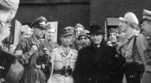 Grupp av män, varav en med hatt och rock, möjligen Otto Skorzeny, omgiven av militärer i uniform.