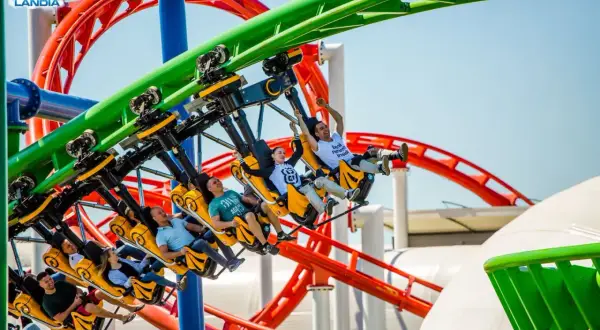 Ludzie krzyczą z radości na żółtych wagonikach rmf dragon roller coaster w Energylandii.