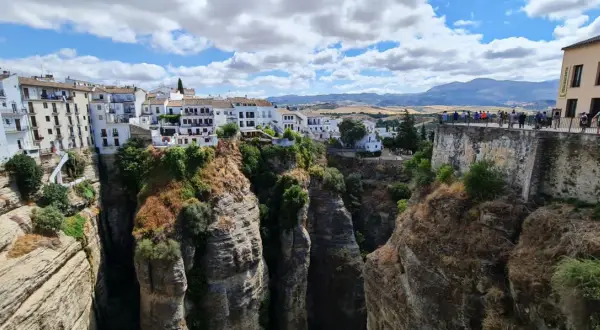 El mirador La Hoya del Tajo ofrece vistas espectaculares de casas blancas al borde de un profundo tajo, con gente admirando el paisaje.