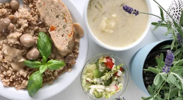 Kotlet mielony z kaszą, grzybami i surówką, obok miseczka zupy i lawenda.