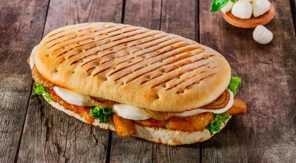 Ein gegrilltes Panini mit Hähnchen, Mozzarella, Salat und karamellisierten Zwiebeln. Ein leckeres panini rezept für jeden Tag.