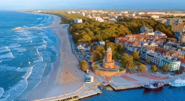 Malownicze polskie wybrzeże miejscowości z latarnią morską, plażą i portem.