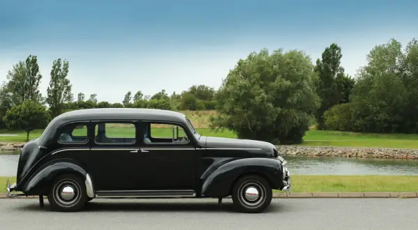 En svart, klassisk Volvo står parkerad vid en sjö. Denna gamla skönhet är en riktig sugga bil, perfekt för en tidlös resa.