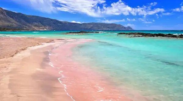 Różowy piasek na Elafonisi beach, turkusowa woda i góry w tle. Raj na ziemi.