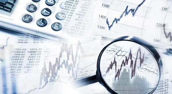 Analiza wykresów i tabel finansowych, kalkulator i lupa wskazują na analizę obligacji korporacyjnych emisji.