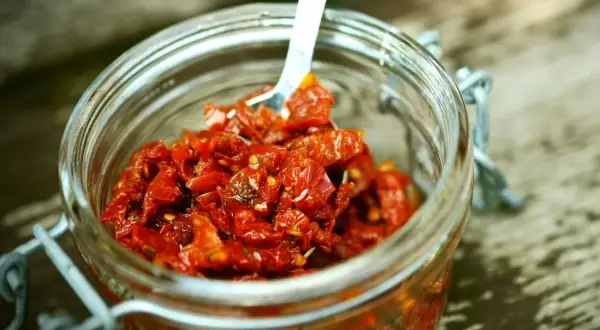Słoik pełen aromatycznego, czerwonego pesto z suszonych pomidorów, gotowy do użycia.