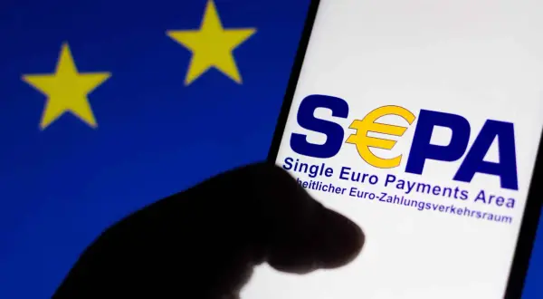 Logo SEPA na ekranie telefonu, na tle flagi UE. Czy w Albanii można płacić euro? SEPA to obszar jednolitej płatności w euro.
