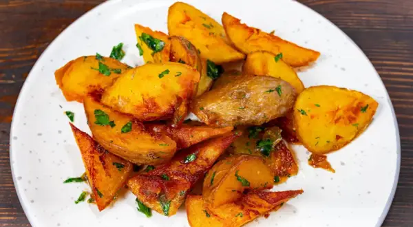 Pommes de terre rôties, coupées en quartiers et parsemées de persil frais. Une recette simple et savoureuse pour un accompagnement parfait.