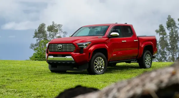 Czerwona Toyota Tacoma na zielonej trawie, gotowa na przygodę.