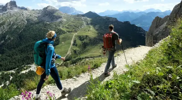 Dos personas disfrutan de un día de trekking hiking por un sendero montañoso con vistas espectaculares.