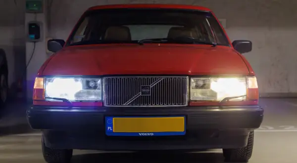 Czerwone Volvo z włączonymi światłami. Czy ledy mogą się zapalić? Tak, te świecą jasno, oświetlając parking.
